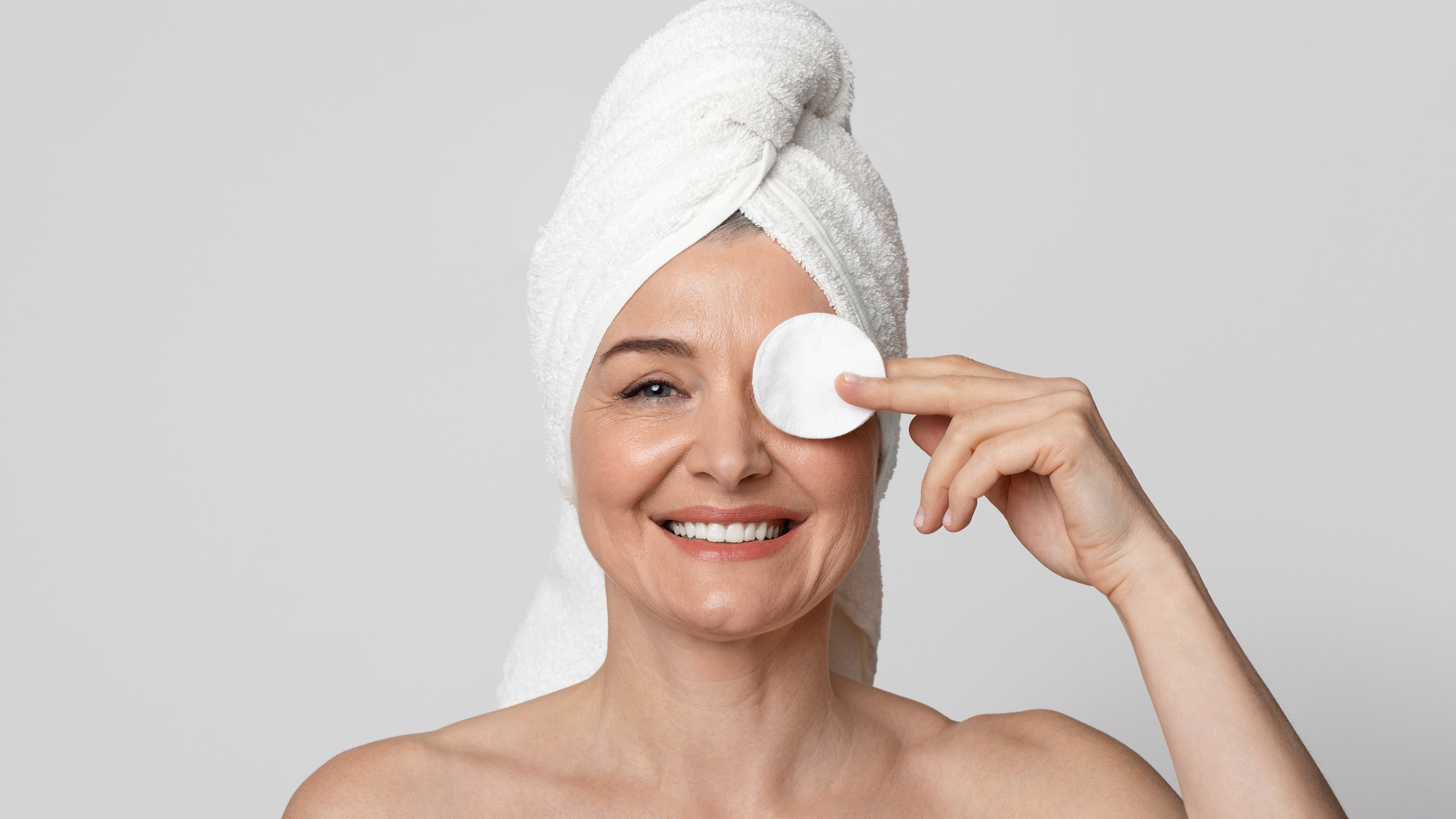 photo d'une femme mature avec une serviette dans les cheveux et un coton sur un oeil